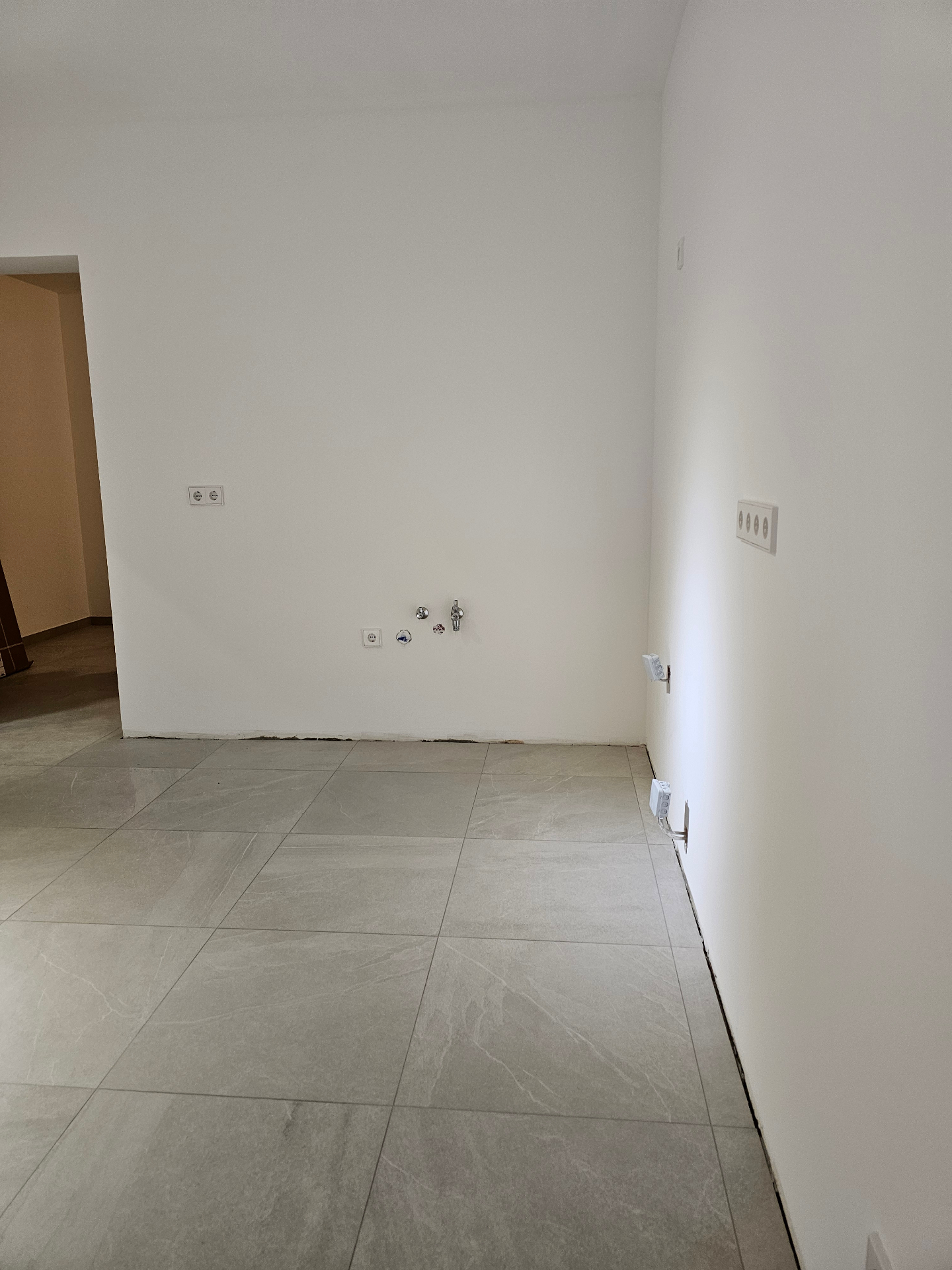 Freshly tiled room with new plumbing and sockets ready for the kitchen