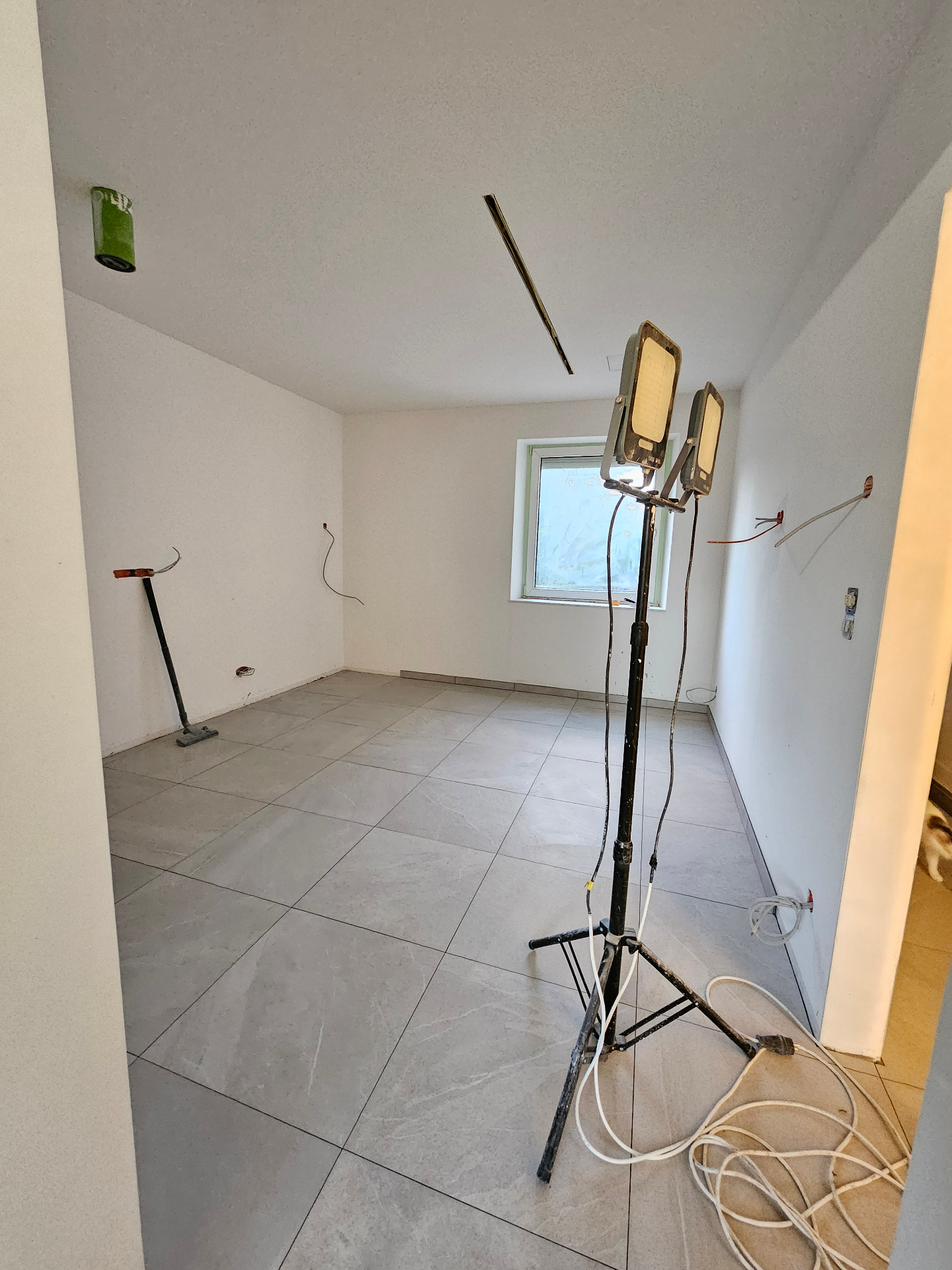 Newly tiled room lit by work lights, ready for finishing