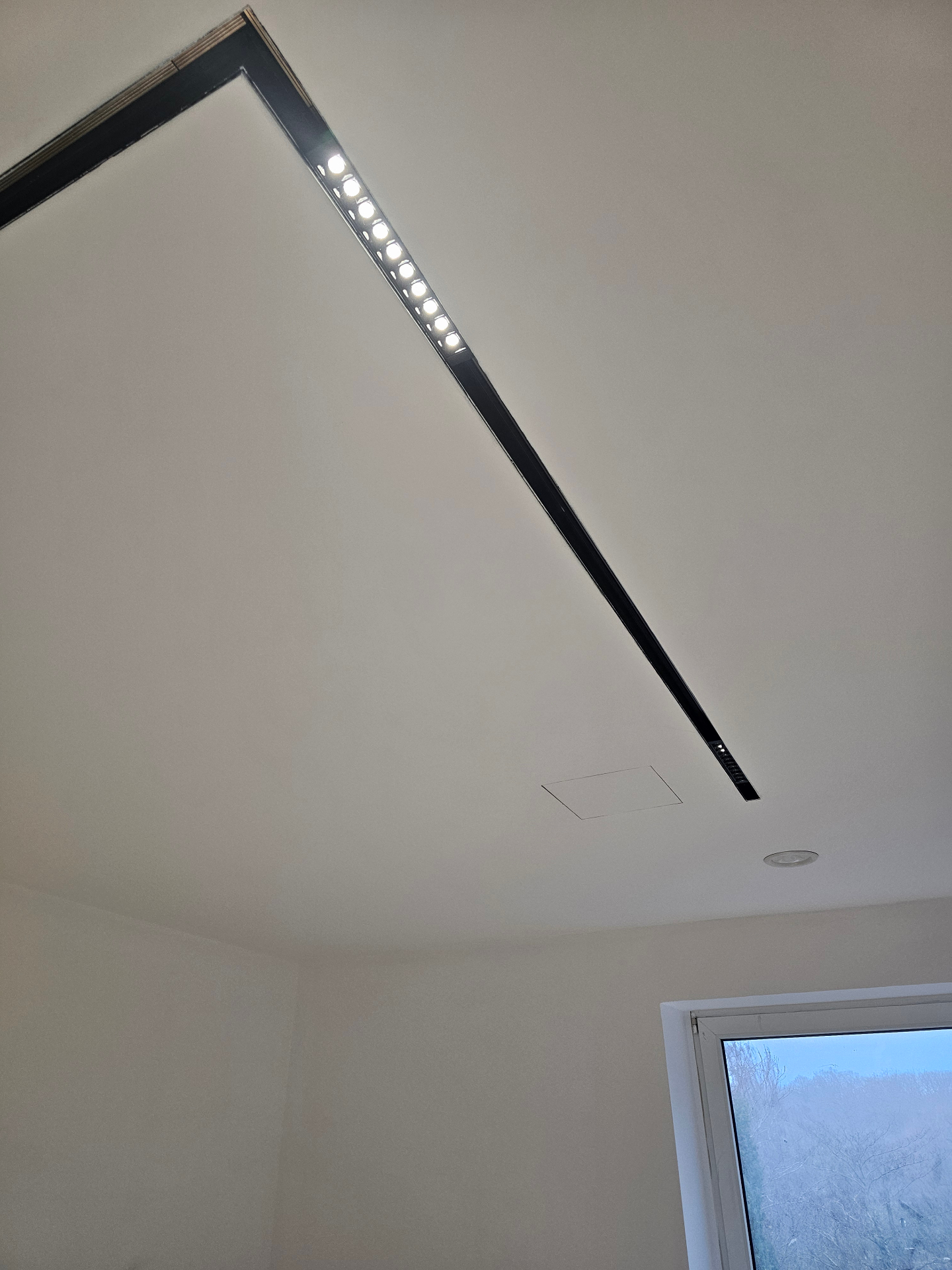 Minimal black ceiling light integrated into a finished room